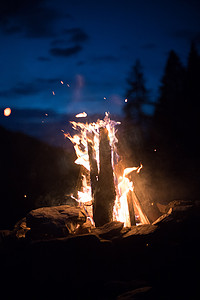 红色火焰摄影照片_在夏天，森林里用黄色和红色的火焰露营篝火。
