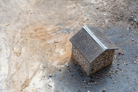 一栋棕色砖砌小楼，屋顶铺在干燥的泥土上，周围是岩石