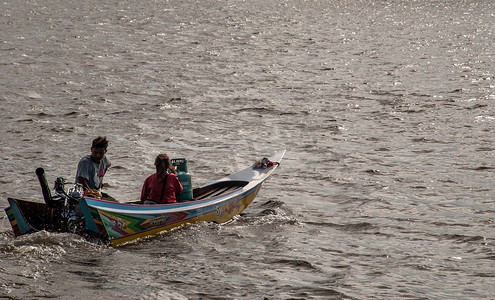 冲在湄南河水面上的长尾船将乘客送过渡口。