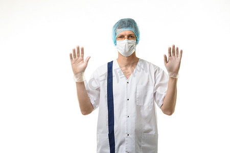 男医生举起手站着，戴着手套，头上戴着面具和帽子