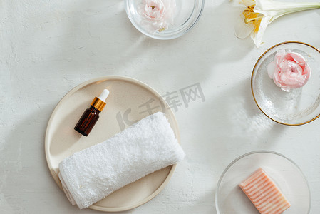 洗澡肥皂摄影照片_Spa 产品的顶部视图，盘子上有毛巾和油、鲜花、白色背景的肥皂