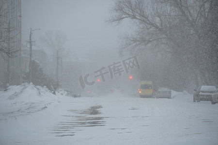 在暴风雨、暴风雪或冬季降雪中，在城市的恶劣天气下，一条空荡荡的积雪覆盖的道路。