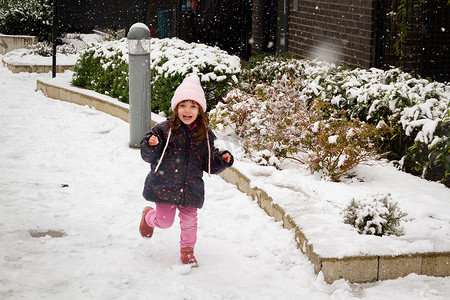 一个戴着粉色帽子的女孩在雪地里玩耍