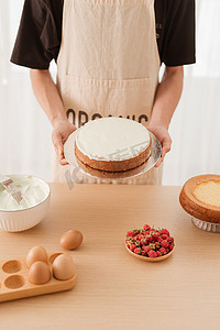 马斯卡彭摄影照片_拿着海绵蛋糕的男性糕点师。