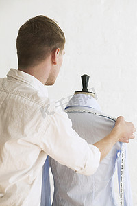 时尚工作室裁缝模型上年轻男裁缝测量衬衫的后视图