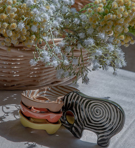 一套房子摄影照片_一套大象形状的陶瓷杯和编织篮子里的一束鲜花，将房子装饰得很漂亮。