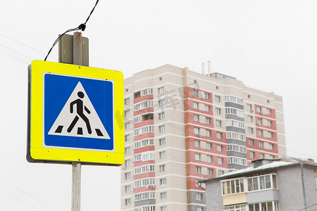 安全警示灯摄影照片_人行横道路标矗立在一座高层建筑旁边。