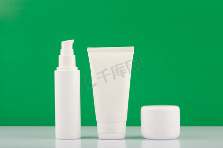 绿色背景下白色光滑桌子上用于日常美容的有机化妆品