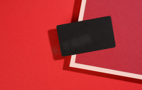 名片黑色创意摄影照片_空白黑色矩形名片位于现代红色背景上，红色纸片带有阴影。
