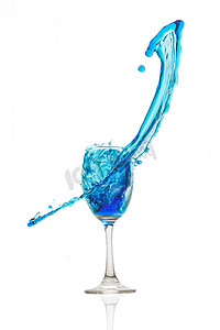 在白色背景的酒杯丝毫蓝色水飞溅。