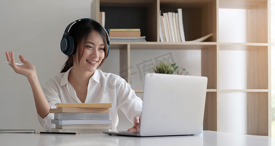 侧视头像微笑的混血女士戴着耳机，通过视频计算机通话与客户沟通。