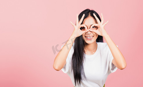 女人站着，她用手指 OK 符号表示同意靠近眼睛