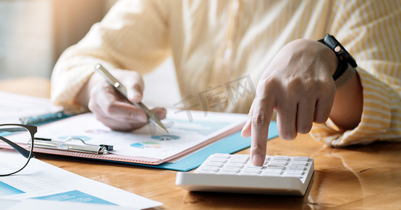 使用计算器、会计财务概念在办公桌上工作的会计师或簿记员。