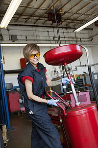 在车库里从事焊接设备工作的快乐女机械师的画像