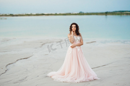 穿着粉红色连衣裙的女孩正沿着白色沙滩行走