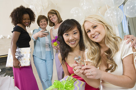 新娘和她的朋友坐在一起，在新娘送礼会上展示大订婚戒指