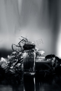 精华液摄影照片_木质表面上的一束鸡腿花及其提取的基本浓度或精华液，装在一个小透明玻璃瓶中。