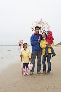 沙滩上带伞的幸福家庭