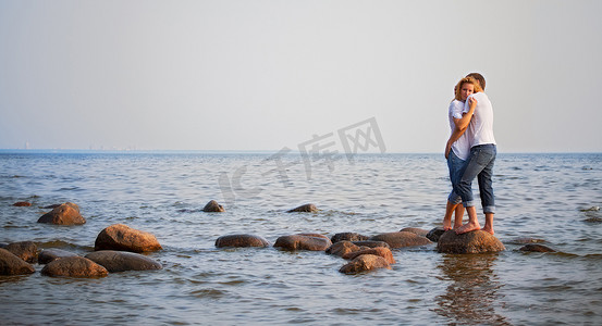 水拥抱摄影照片_情侣拥抱在海中的一块石头上