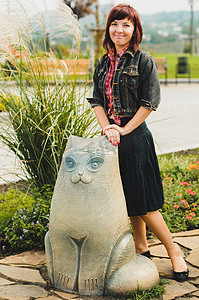 站在滑稽的猫雕像旁边的年轻女人