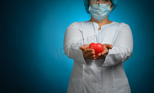 一件白色外套的女性军医，面具站立并且拿着在蓝色背景的红色心脏