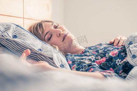 健康睡眠摄影照片_宁静的睡眠：年轻女性睡在她的床上，特写
