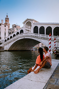 一对男女在意大利威尼斯的城市之旅中，色彩缤纷的街道上有运河威尼斯