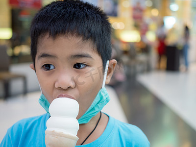 一个男孩在背景模糊的商场里吃冰淇淋。