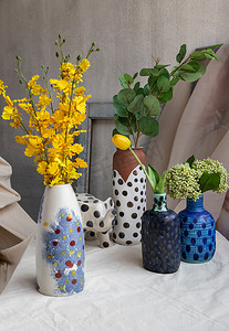 白色纹理桌布上手工制作的许多花束，各种不同的陶瓷波尔卡圆点花瓶和大象形陶瓷。