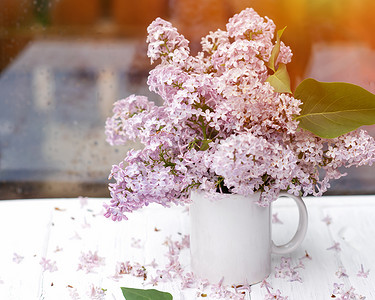 春天下雨天，复古木质表面上有淡紫色的白色杯子。