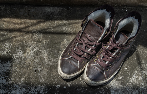 棕色复古高帮帆布运动鞋被放置在旧水泥地板上。