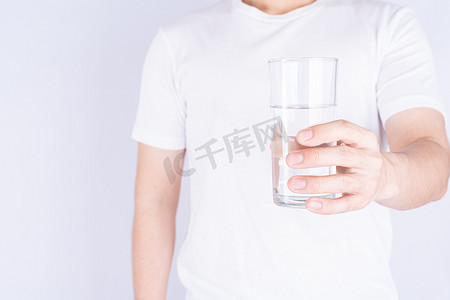 拿着杯水的人隔绝了灰色背景。
