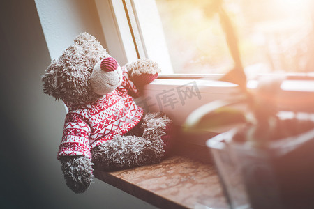 正泰电工logo摄影照片_离开概念：泰迪熊正看着窗外，阳光