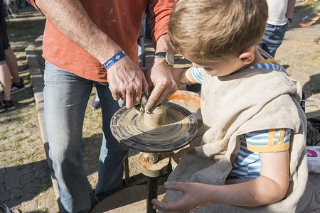 乌克兰，卢茨克 — 2019 年 6 月 5 日：一个成年男子的手教孩子如何在美食节上用陶轮上的一块粘土制作一个水壶。