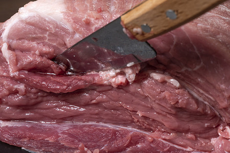 在特写镜头中用刀将猪肉或牛肉切成薄片。肉类菜肴和食品的准备。烤羊肉串、烧烤或烤肉串用的红肉片。用刀切生鲜肉。食谱
