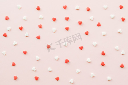 红色小爱心摄影照片_情人节背景，粉红色背景上有红色和白色的小爱心。