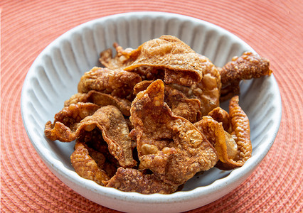 泰国传统小吃，红色背景白碗里的脆皮炸鸡皮。
