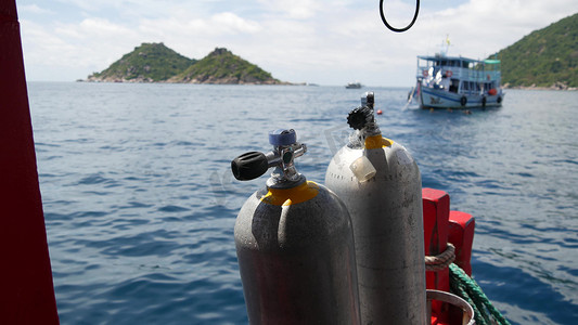 在泰国涛岛度假村附近波涛汹涌的海洋中，一排氧气罐和潜水设备被放置在现代船上。