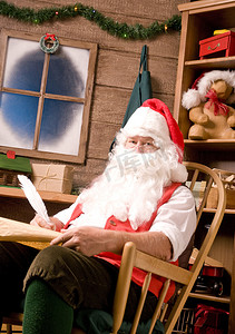 圣圣诞老人摄影照片_圣诞老人在车间里用鹅毛笔和淘气清单