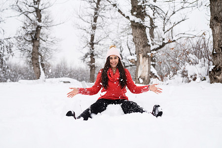 穿着红色毛衣的黑发年轻女子在公园里玩雪