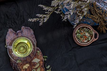 藏红花杯子摄影照片_一杯香兰叶茶，印度沼泽飞蓬植物叶与红花干（藏红花替代品）在深色背景下。