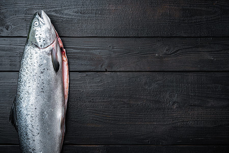 综艺文字摄影照片_黑色木质表面的鲜生鲑鱼红鱼片，平铺，有文字空间