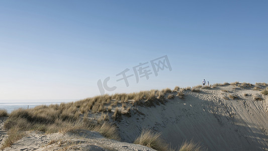 父子爬摄影照片_春天阳光明媚的日子，父子在蓝天下爬沙丘