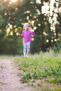 在夏田的草地后面奔跑的小女孩剪影