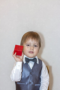 一个小男孩拿着一个红色的盒子，递过来，这是情人节的主题概念。