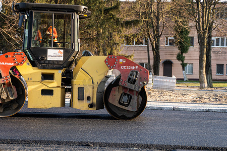 KYIV, UKRAINE - September 10, 2020：带有重型振动压路机的重型沥青压路机在街道道路施工现场的道路上压上新的热沥青。