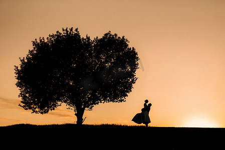 橙色夕阳背景下一对快乐的年轻男女的剪影