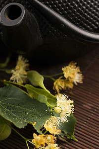 木制茶壶摄影照片_茶壶和杯子用菩提树茶和花