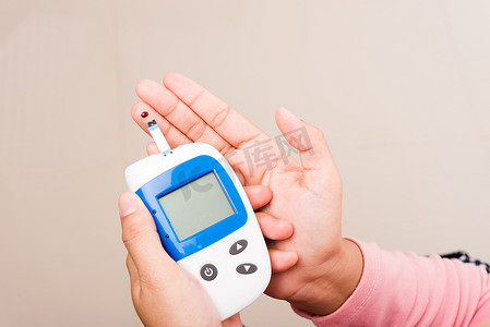 血糖仪主图摄影照片_女性用血糖仪测量手指上的血液葡萄糖测试水平检查