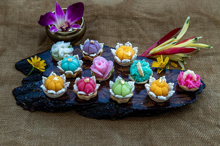 各种优雅美丽的泰式甜点 (Khanom Wan Thai) 五颜六色的变化在深色木头中供应，金色和不同花朵形状的叮咬，泰式甜点，吉祥甜点。
